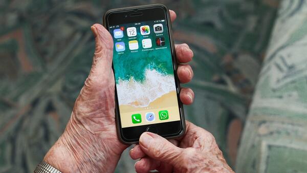 Ein alter Mensch hält ein Smartphone in der Hand